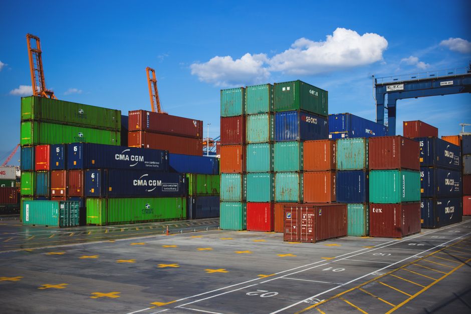 Container vessels working a transhipment hub — outer ports like Khor Fakkan and Sohar are taking the upper-Gulf feed